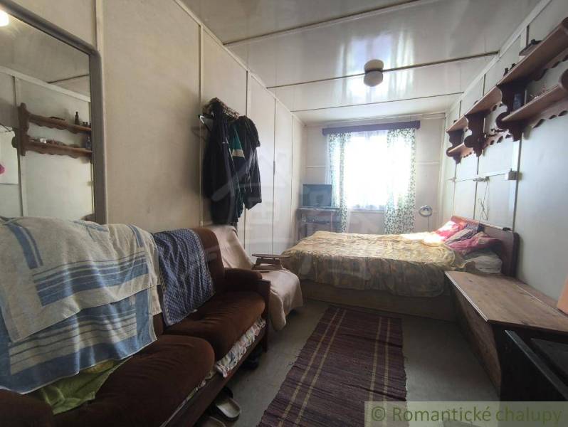 A room with a sofa, bed, and window, part of a cabin, cozy interior.