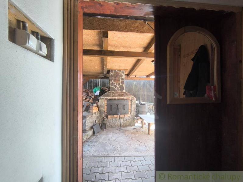 View from the cottage to the outdoor oven and yard with wood in Hronská Dúbrava.