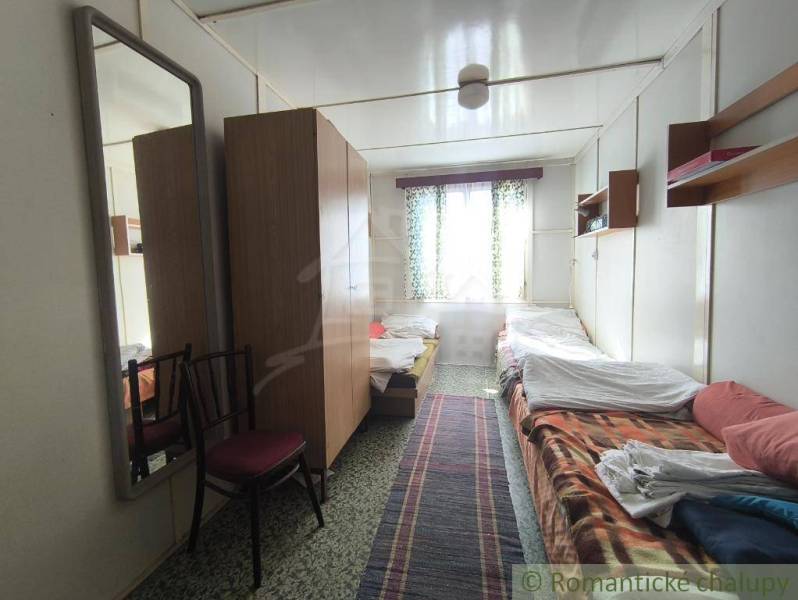 The interior of a cabin with two beds, a narrow carpet, and wooden cabinets.