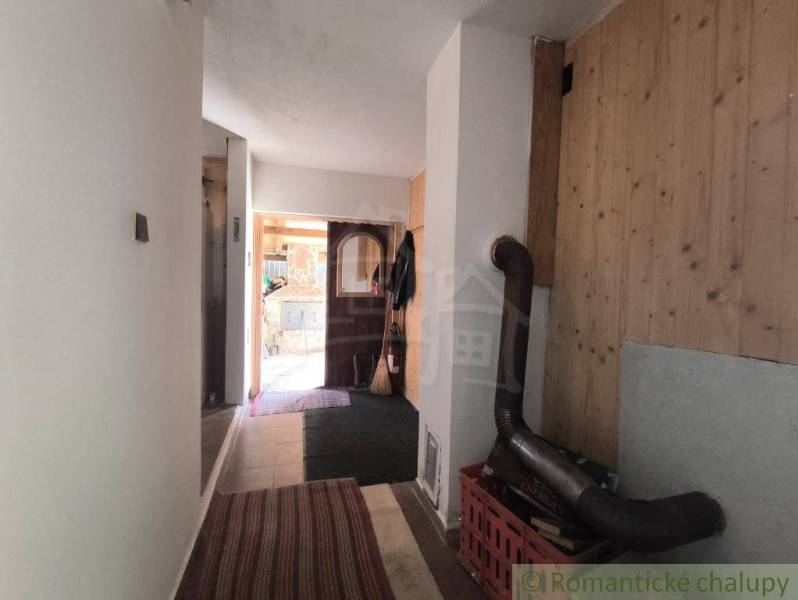 A hallway in a cottage with a wooden decor floor and a wood-burning stove.