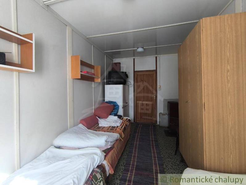 A cozy room in a cabin with a bed, a wardrobe, and shelves on the wall.