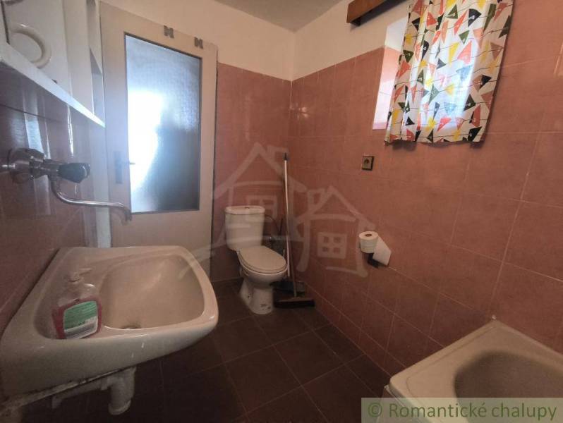 A bathroom in a cabin with basic sanitary facilities and colorful curtains.