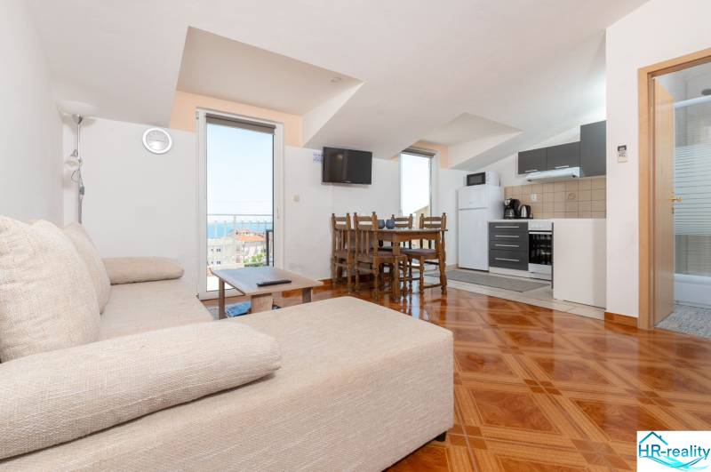 Living room in a holiday apartment with a kitchen and sea view, floor with wood decor.