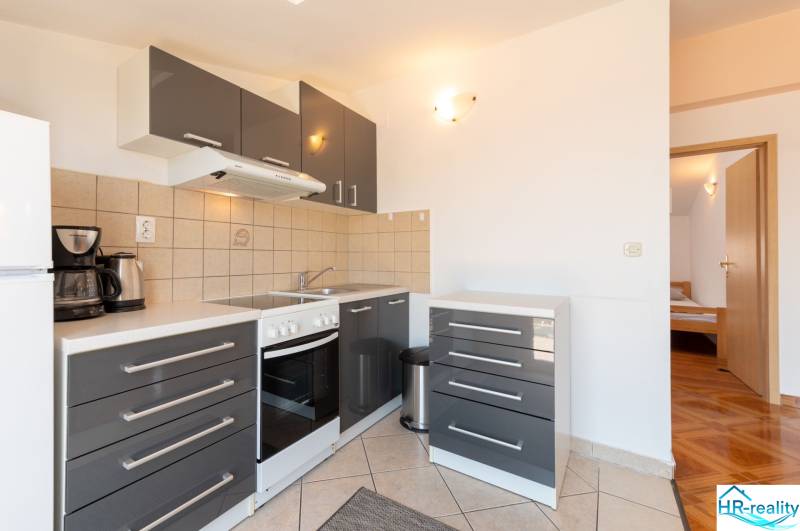 A kitchen in a holiday apartment with dark gray cabinets and tiled flooring.