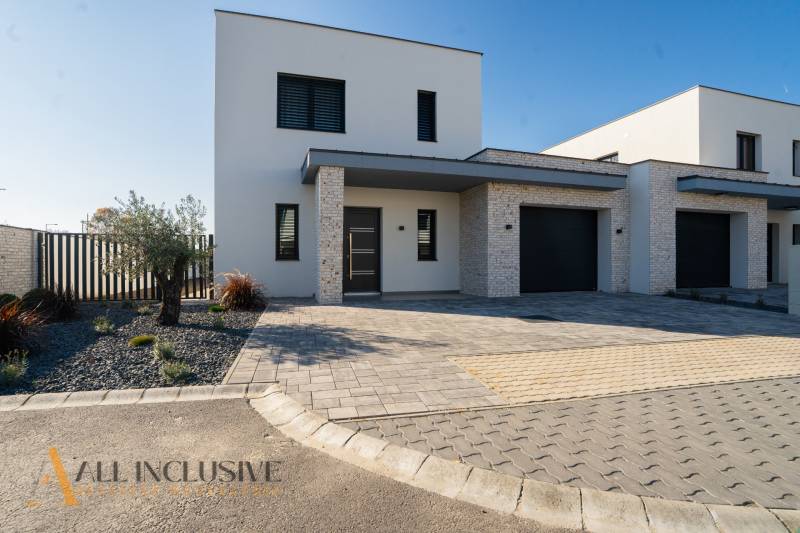 The family house in Gyor-Moson-Sopron has a minimalist facade with a garage and a landscaped garden.