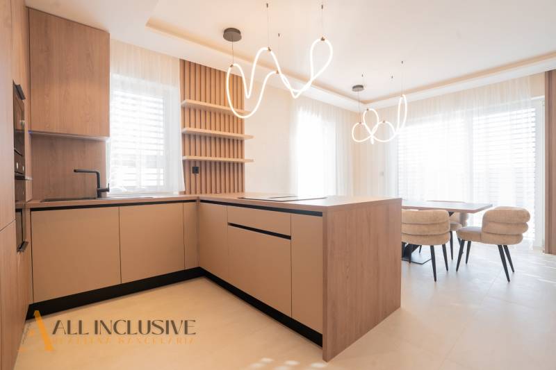 A kitchen in a family house with an island, modern lighting, and a wooden decor floor.