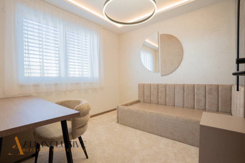 Bright room in a family house with a bed, table, and mirror on the wall.