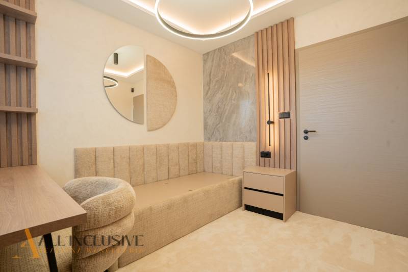 A bright room with a beige sofa, a round mirror, and a table in a family house.