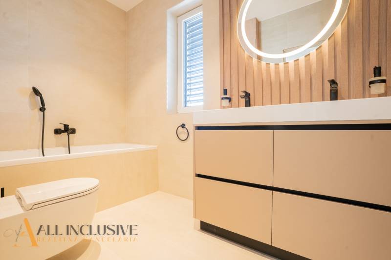 Bathroom in a family house with a bathtub, mirror, and window, wooden decor.