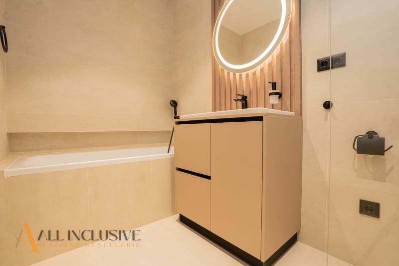 A bathroom with an oval mirror and a bathtub in a family house.