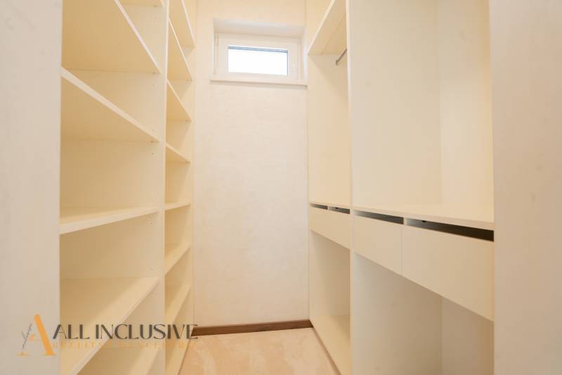 Bright dressing room in a family house with shelves and a window.