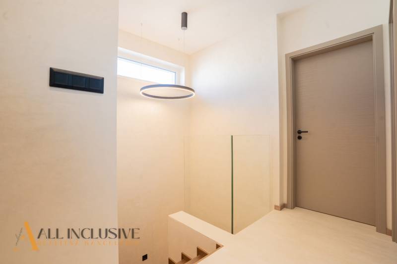 Interior of a family house with a coat rack, doors, and a staircase in a neutral color scheme.