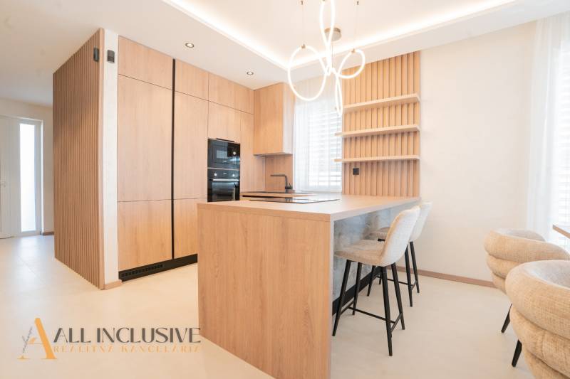 A kitchen in a family house with a wooden decor floor and pendant lighting.