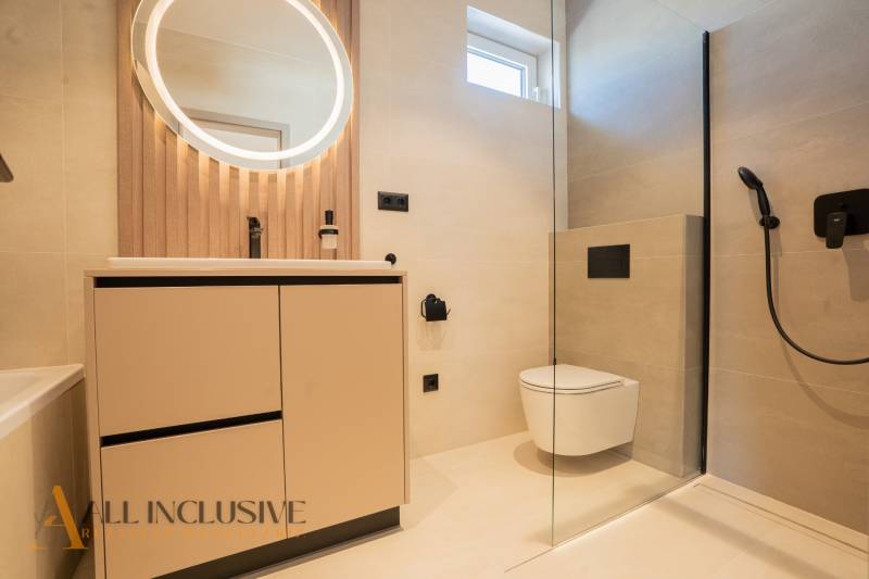 Bathroom in a family house with a round mirror, shower, and toilet.