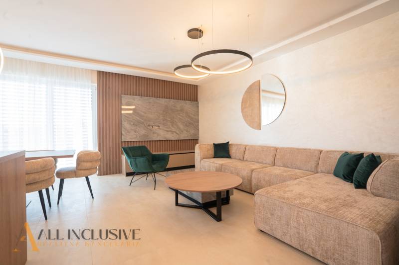 Living room in a family house with a beige sofa, green armchair, and a round table.