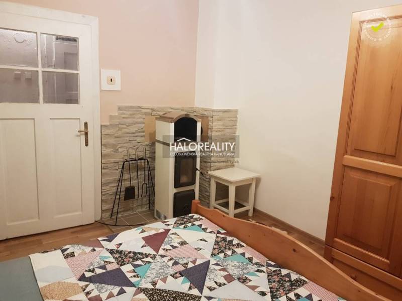 In the family house, there is a room with a stove, a bed, a cabinet, and a floor with a wooden decor.