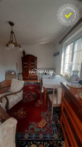 A traditionally furnished living room in a family house with a red carpet and wooden furniture.
