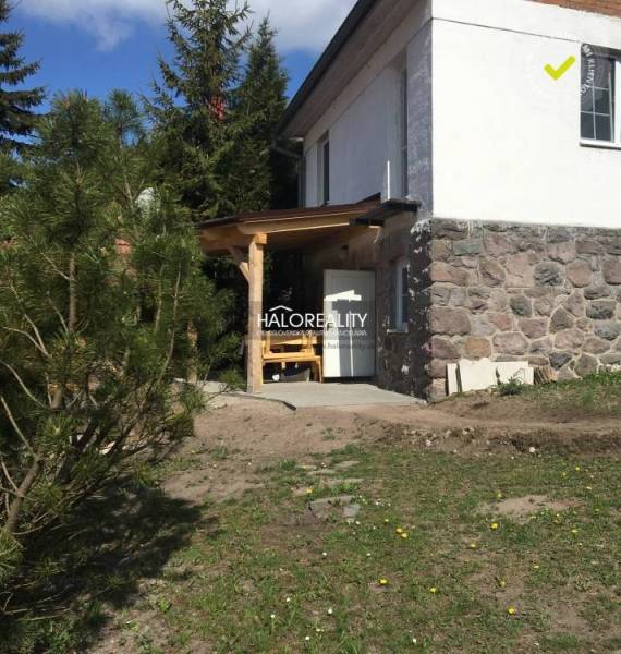 A family house in Turček with a stone foundation and a wooden shelter in the garden.