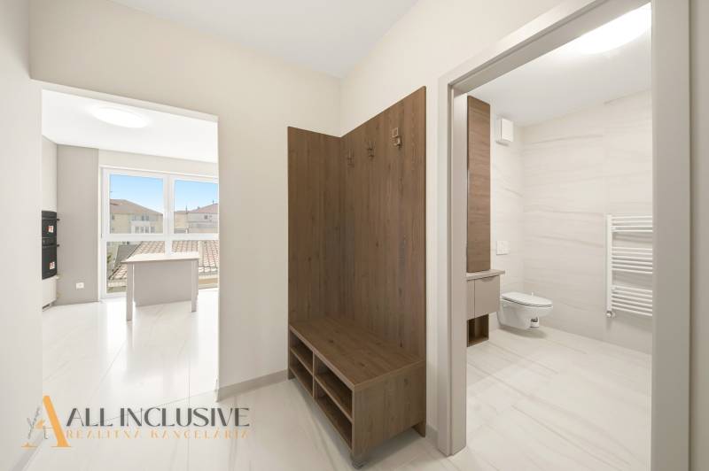 Entrance hall with a bench and a bathroom in a 2-room apartment with a wooden decor floor.