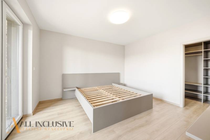A bedroom in a 2-room apartment with a bed and a floor with a wood decor.