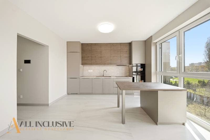 A kitchen in a 2-room apartment with a wooden decor floor and large windows.