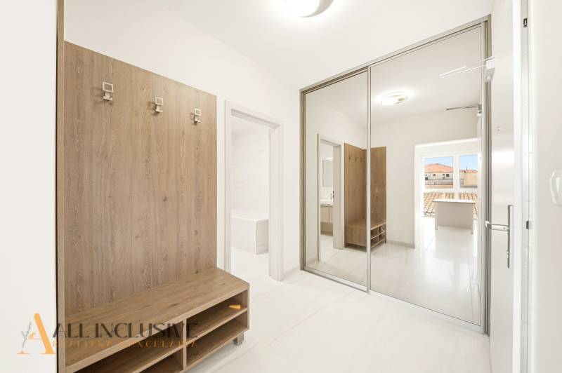 An entrance hall in a 2-room apartment with a mirrored wardrobe and a wooden wall hanger.