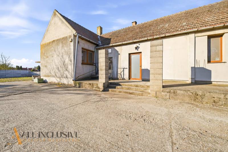 Exterior of commercial premises in Jelka with a concrete yard and a sloped roof.