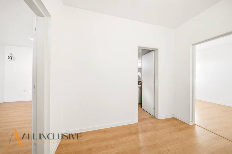 White walls, wood-patterned flooring, and two open doors in commercial premises.