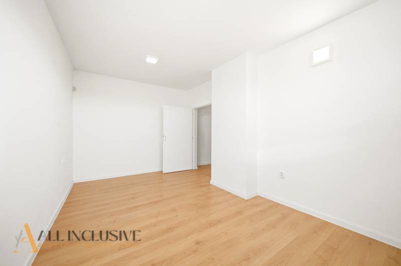 A spacious room in commercial premises with a wooden decor floor, white walls.