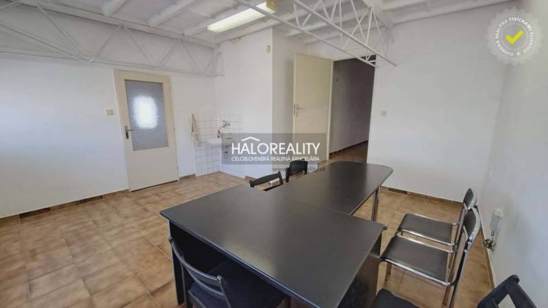 An office interior with ceramic flooring, a desk and chairs, a sink by the wall.