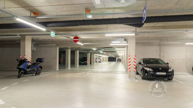 Parking garage with cars and a motorcycle, underground lighting, the space gives a clean impression.