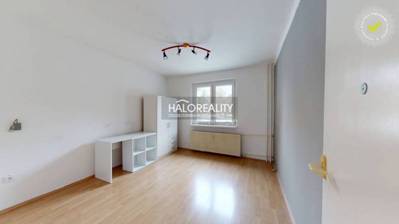 A bright room in a 2-room apartment with a wood-patterned floor and simple furniture.