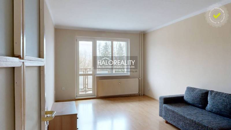 Living room in a two-room apartment with a wooden decor floor and a balcony.