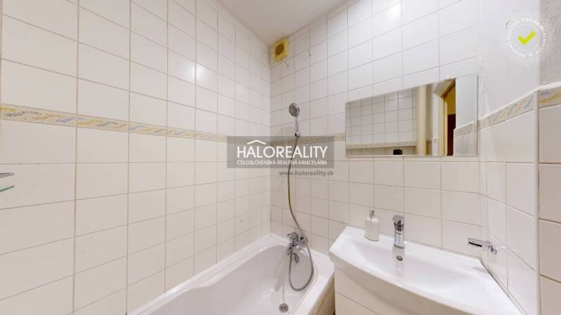 Bathroom with white tiles, a bathtub, and a sink in a 2-room apartment.