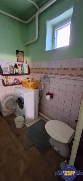 Bathroom with a washing machine and toilet in a family house, floor with wooden decor.