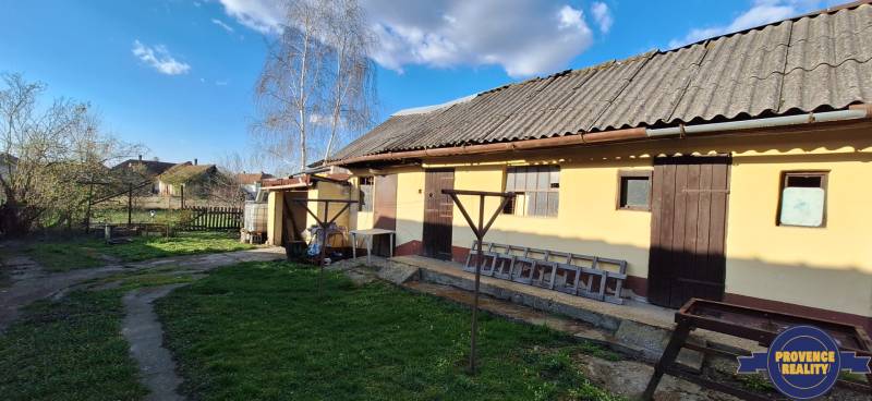 A family house in the village of Holiare with a lawn, trees, and a wooden shelter.