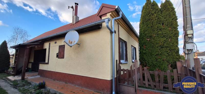 A family house in Holiare surrounded by greenery, with a satellite dish on the facade.