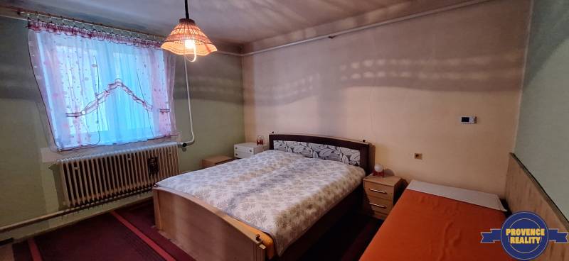 Bedroom in a family house with a bed and curtains by the window.