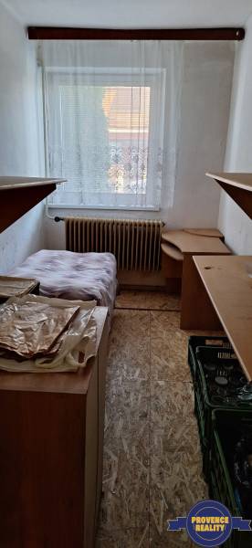 A narrow room with a bed, storage space, and wooden floor decor in a family house.