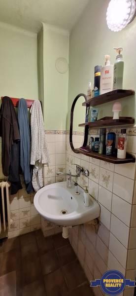 Bathroom with a sink in a family house, with wooden shelves on the wall.