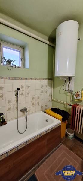 A bathroom in a family house with a bathtub, tiles, and a boiler.
