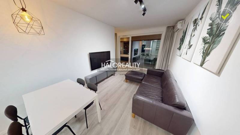 Living room in a two-room apartment with a sofa, television, and a wooden decor floor.