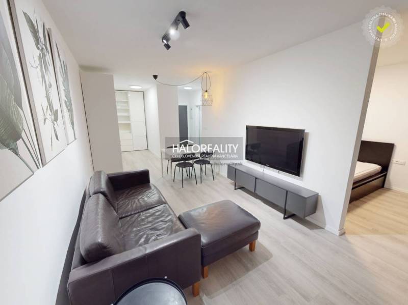 Living room with a leather sofa in a two-room apartment and a floor with a wooden decor.