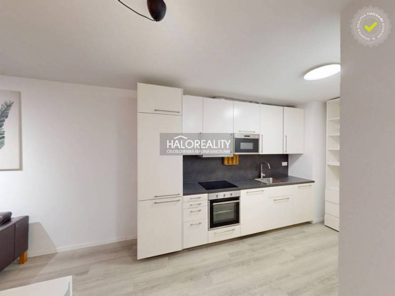 The kitchen of a 2-room apartment with white cabinets and a wood-patterned floor.