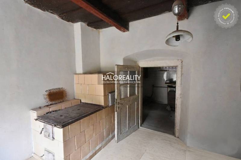 Traditional interior with a tiled stove and wooden ceiling.