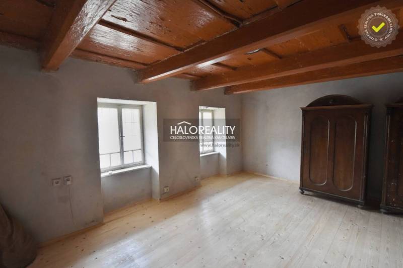 The interior of a cabin with a wooden ceiling, a floor with a wooden decor, and a wardrobe.