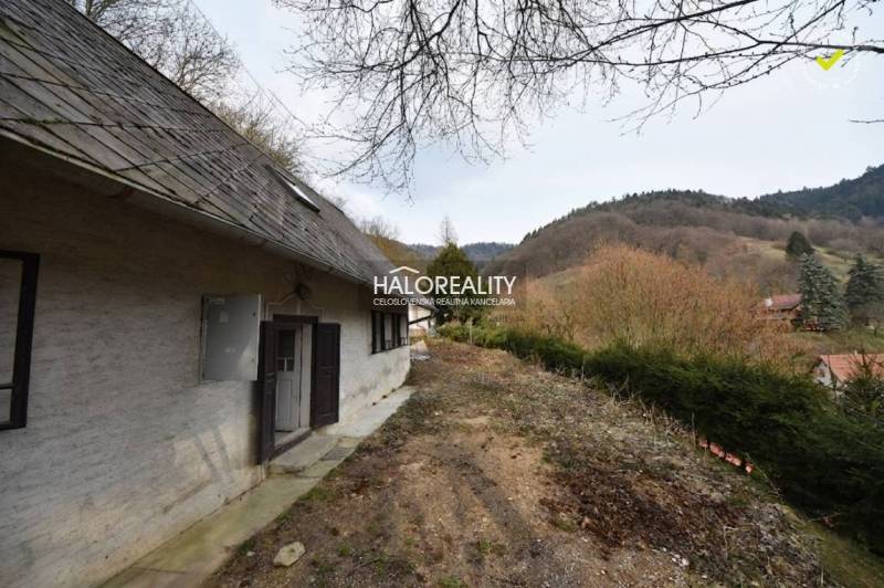 A cottage in Hodruša - Hámre with steep terrain and a view of forested hills.