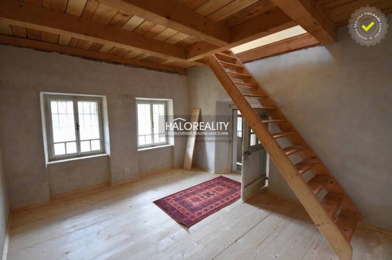 Interior of a cabin with a wooden staircase, a floor with a wooden decor, and a carpet.