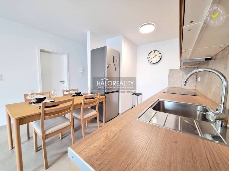 Kitchen in a 2-room apartment with a wooden table, sink, and cooking equipment.