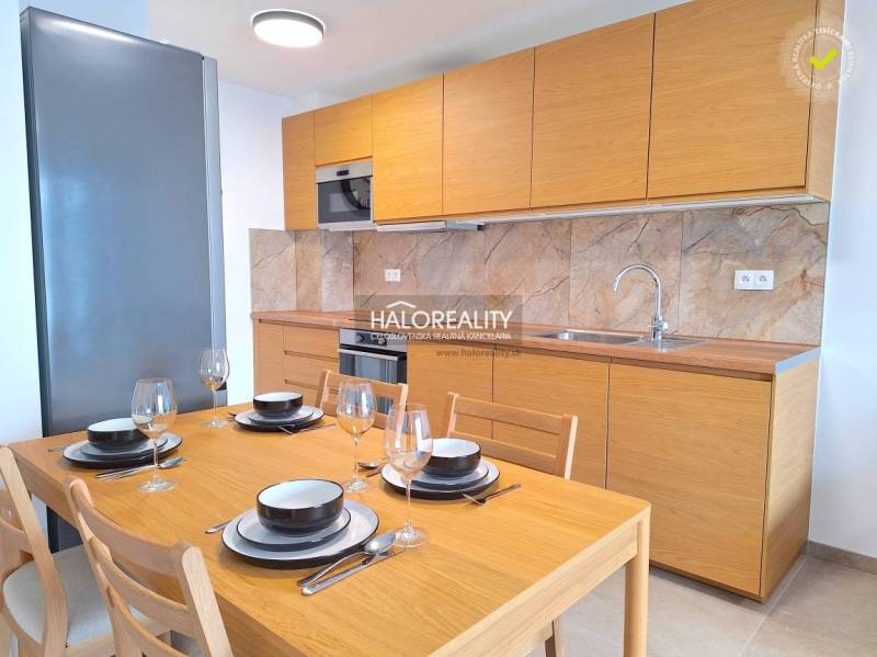 A kitchen in a 2-room apartment with wooden decor, built-in appliances, and marble cladding.